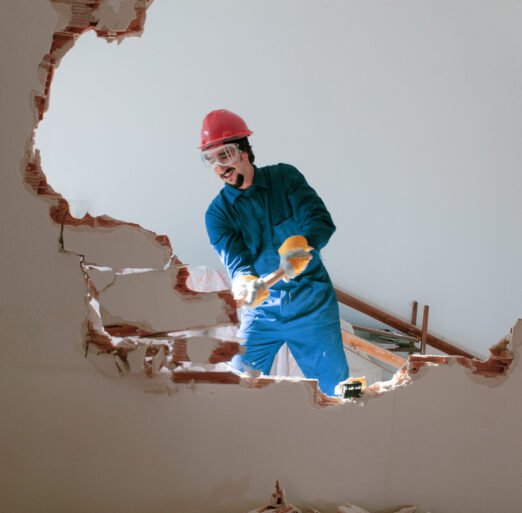 young worker with a red protection helmet and wearing a blue boiler suit. demolition concept